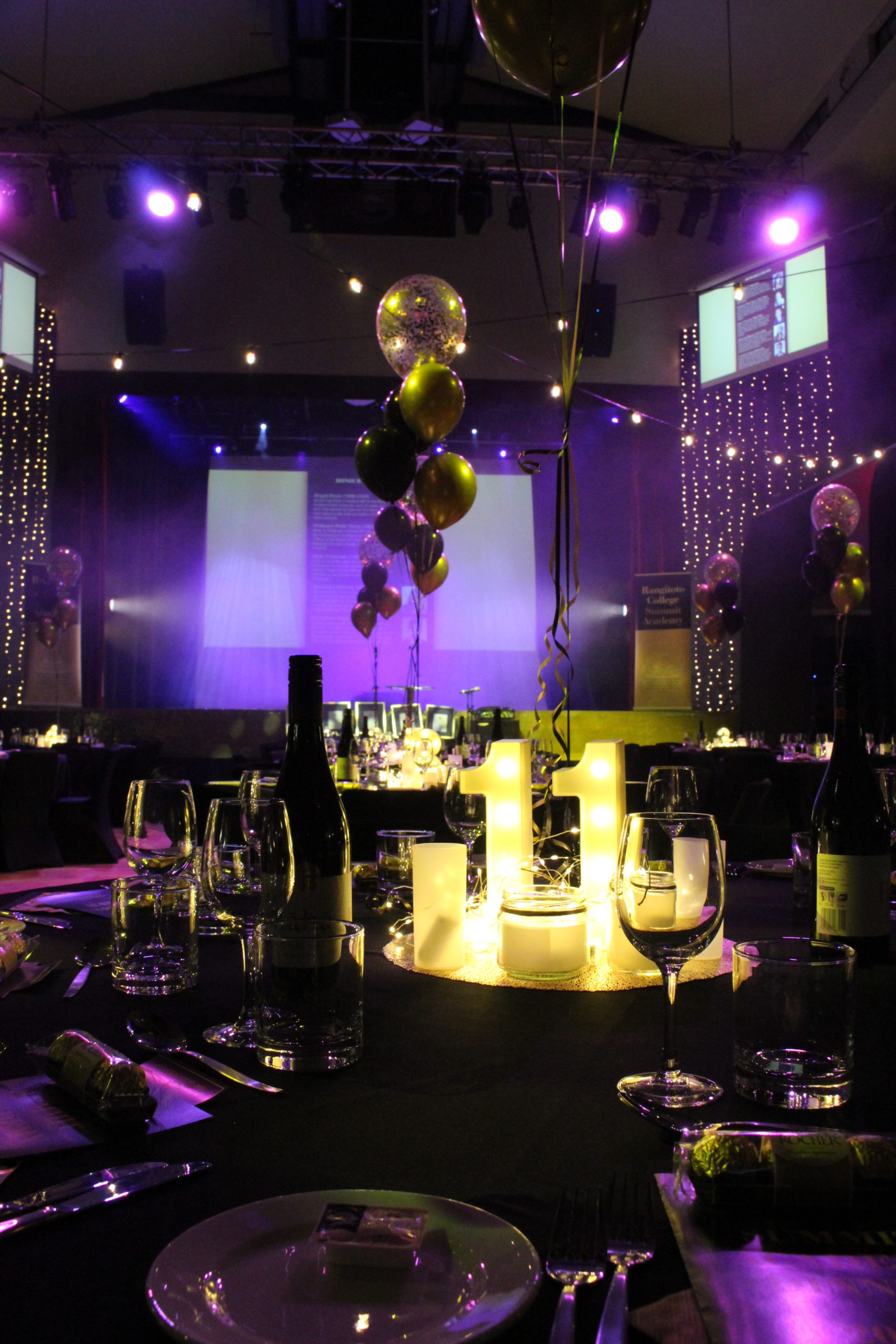 2021 Summit Academy Dinner, Table 11, lit in numbers, with candle and floating gold and black balloons in centre of table